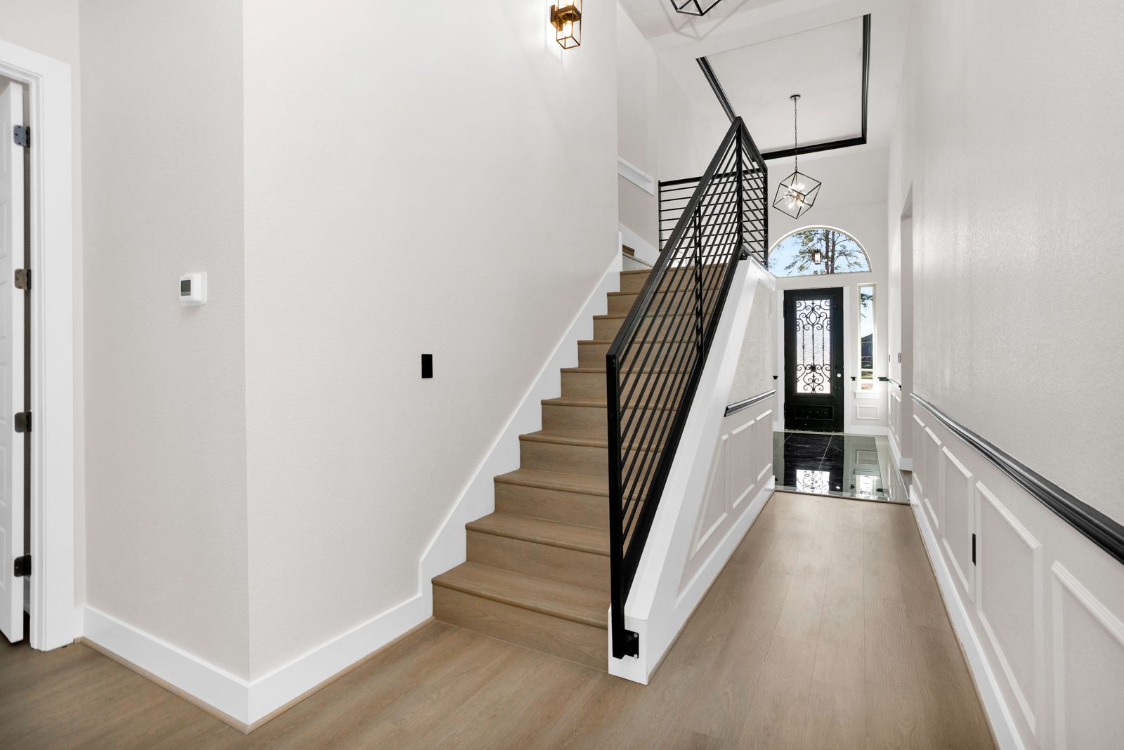 Staircase with iron railing and two-story foyer view